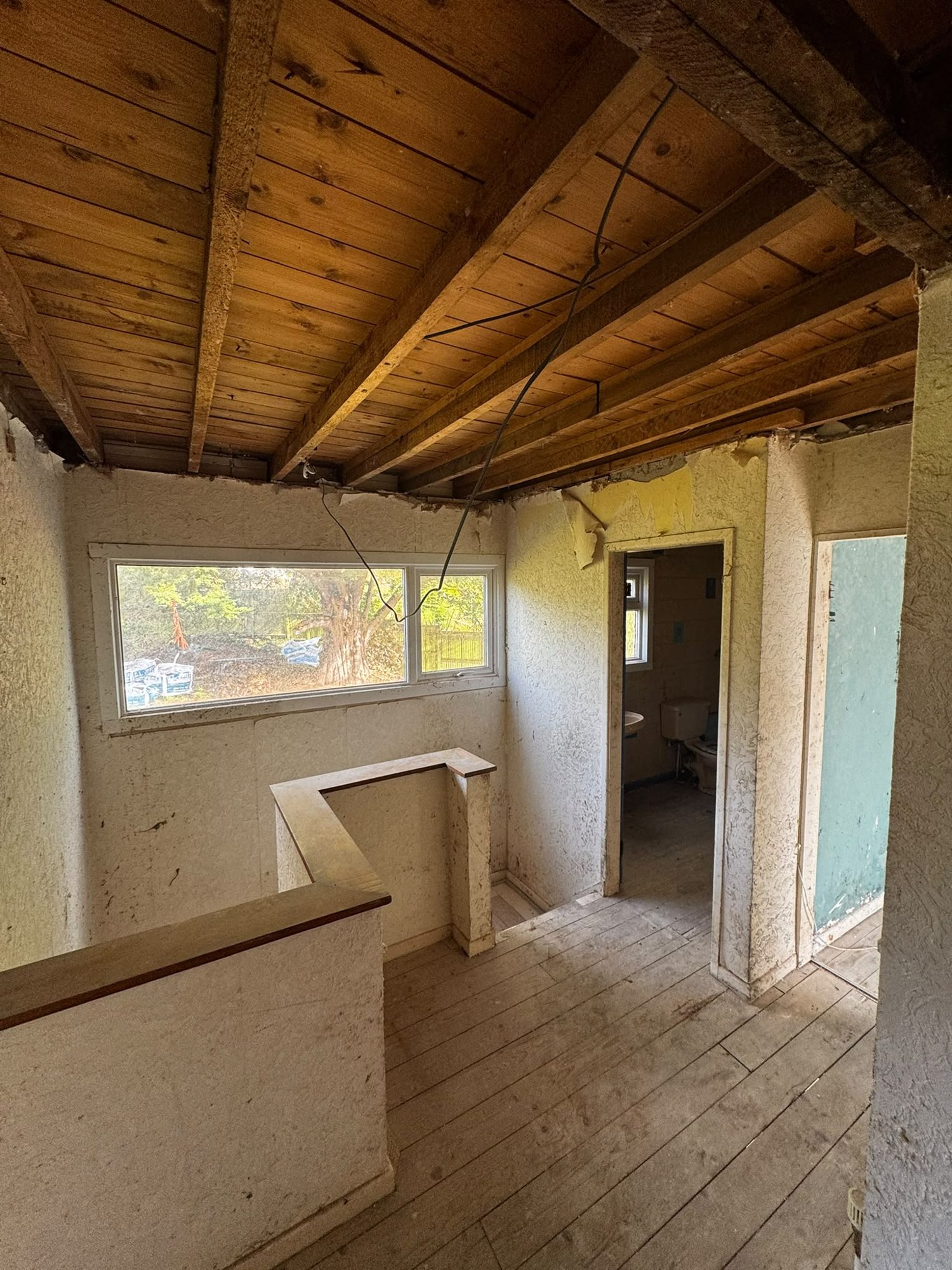 Landing with textured wall coating and ceiling stripped to joists in Anglesey
