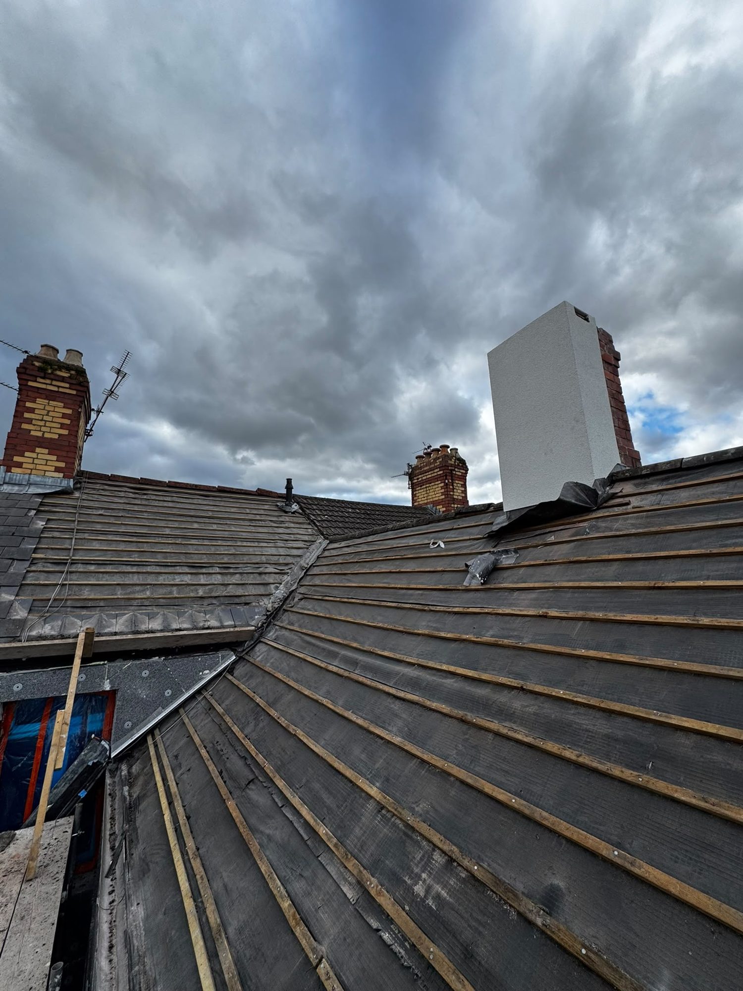 Re-roof in progress with new battens beside chimneys in North Wales