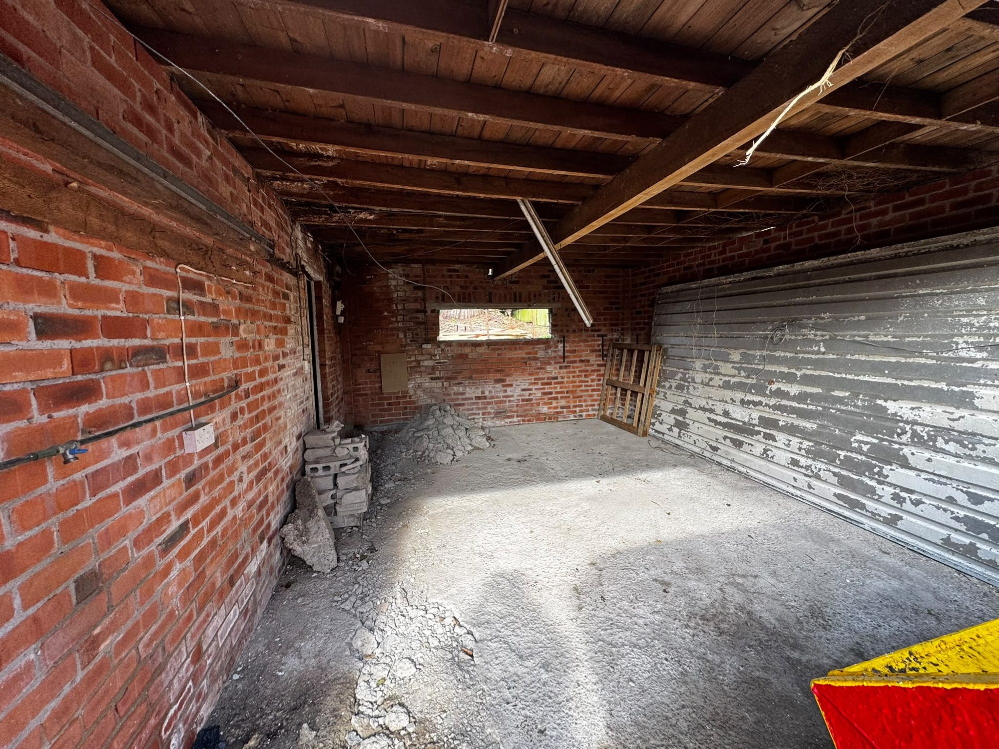Empty brick garage interior after asbestos works in North Wales