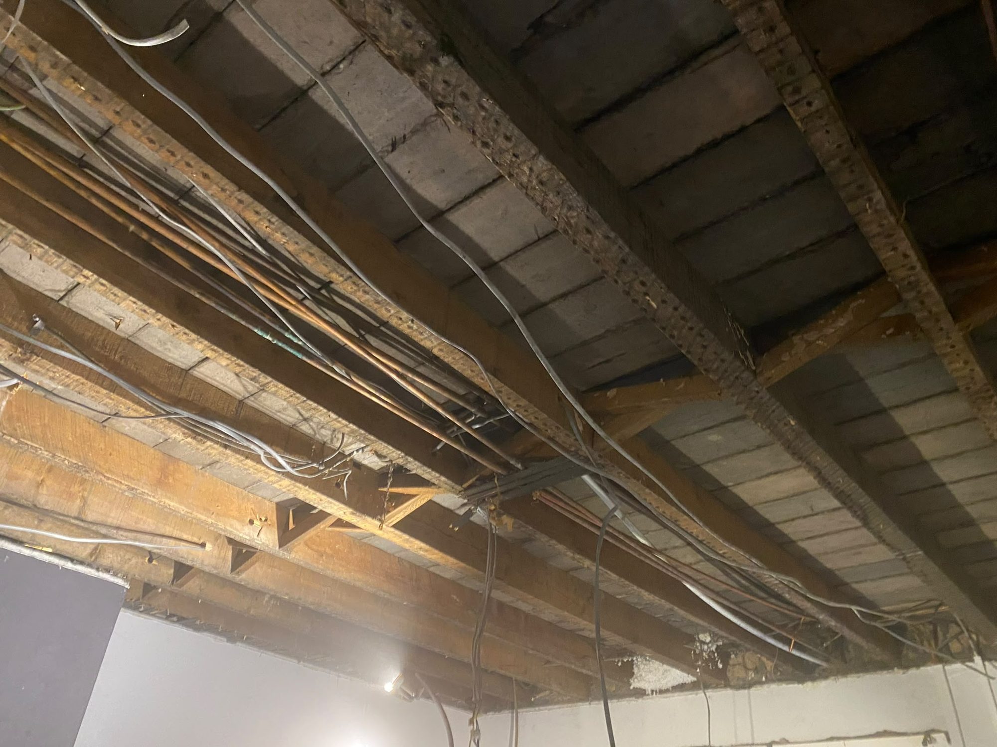 Ceiling joists and services exposed during soft strip in North Wales